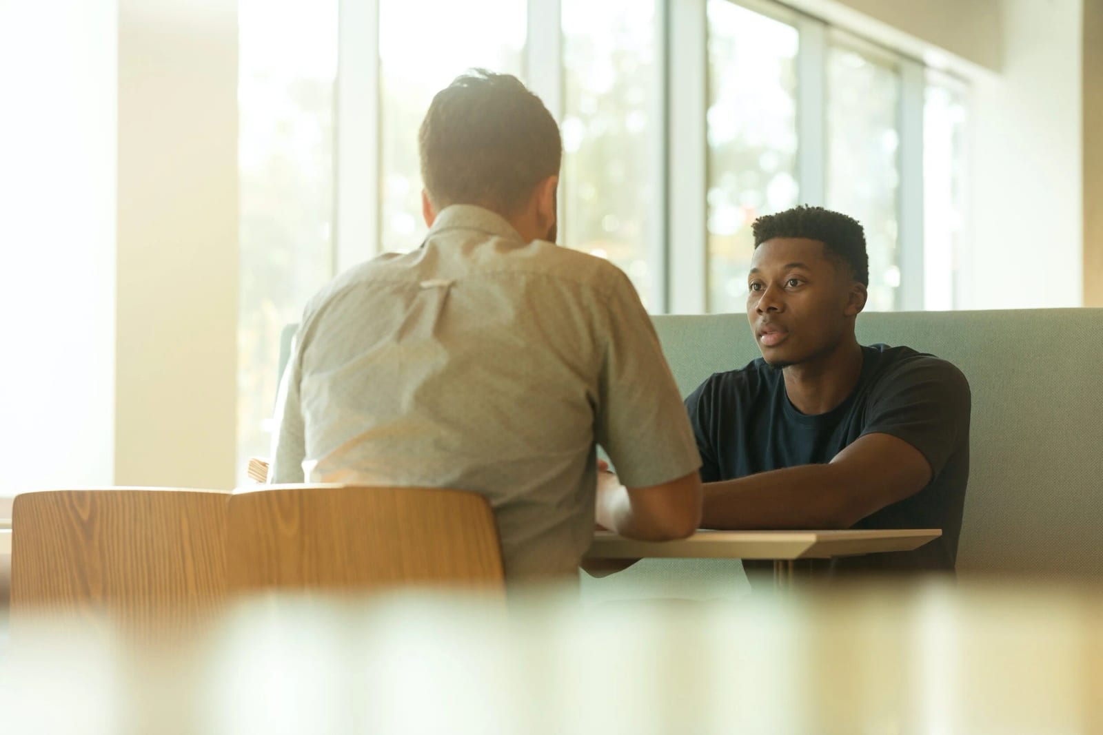 Two men sitting facing each other having a conversation about discipleship.